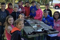 Students standing and sitting around picnic table