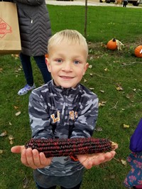 Student holding an ear of corn (2nd Grade Pioneer Day - Fall 2017)