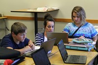 A teacher assisting two students