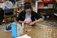 A girl building a popsicle stick bridge