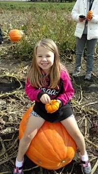 student sitting on a pumpkin