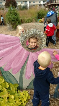 Child looking through head of a painted flower display