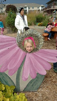 Child looking through head of a painted flower display