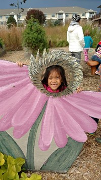 Child looking through head of a painted flower display