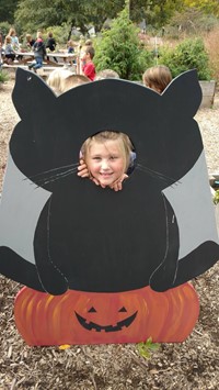 Child looking through head of a black cat display