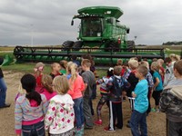 GHV First Grade Students visiting farm with a combine nearby