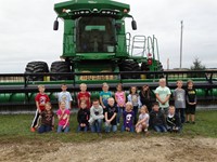GHV First Grade Students visiting farm with a combine nearby