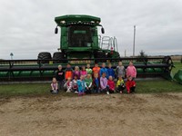 GHV First Grade Students visiting farm with a combine nearby