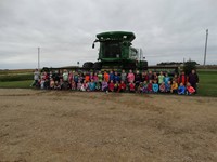 GHV First Grade Students visiting farm with a combine nearby