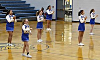 A group of cheerleaders cheering during halftime of a basketball game.
