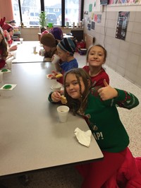 Students sitting at tables eating Christmas cookies
