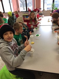 Students sitting at tables eating Christmas cookies