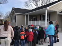 elementary students standing outside a home singing