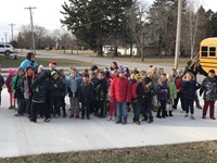 elementary students standing outside a home singing