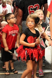 Elementary student walking through tunnel of high school football players