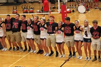 Football players and cheerleaders doing a cheer on the gym floor