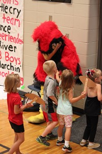 Elementary students walking by Cardinal mascot