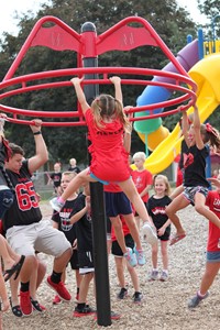 High school students playing with elementary students on playground