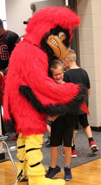 Cardinal mascot hugging elementary student
