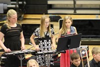 Three girls playing percussion in a band concert