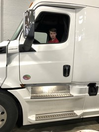 A student sitting in the cab of a semi at a career day