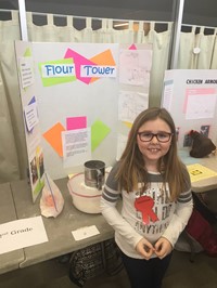 Elementary student standing near her invention, the Flour Tower