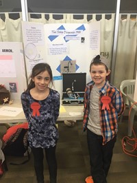 Elementary students standing near their invention, the Soap Dispenser 5000